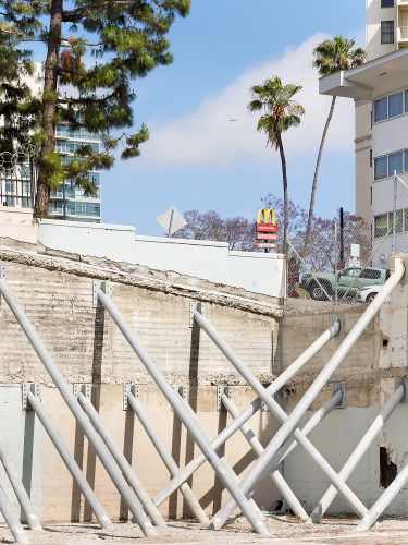 John MacLean CityMcDonalds in San Diego USA seen at top of hill behind buttressed foundations blue sky and plane palm trees