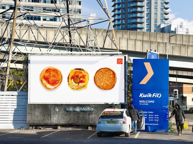 John MacLean SystemStreet scene in Ilford, London. A large roadside billboard shows a McDonald’s hamburger separated into three parts and photographed against a stark white background. Behind it are an overpass, a steel electricity pylon, a blue Kwik Fit sign, and a high-rise tower block. In the foreground, one man gets into a parked white car while another walks past carrying a yellow shopping bag. From the System series.